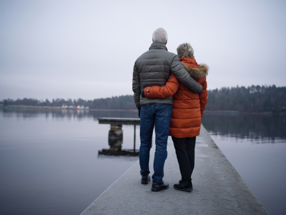 par som står vid vattnet och tittar ut